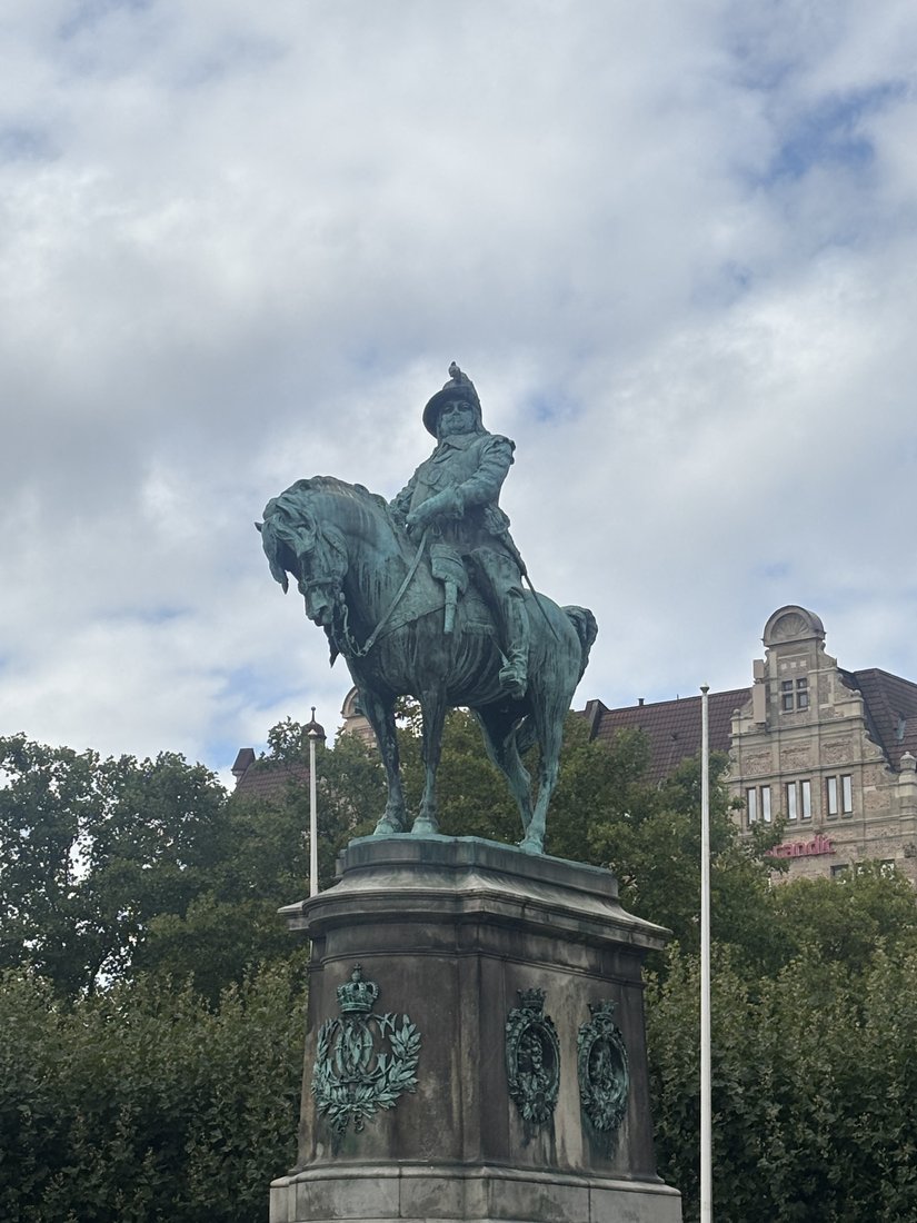 An equestrian monument with a stone pedestal and cloudy sky